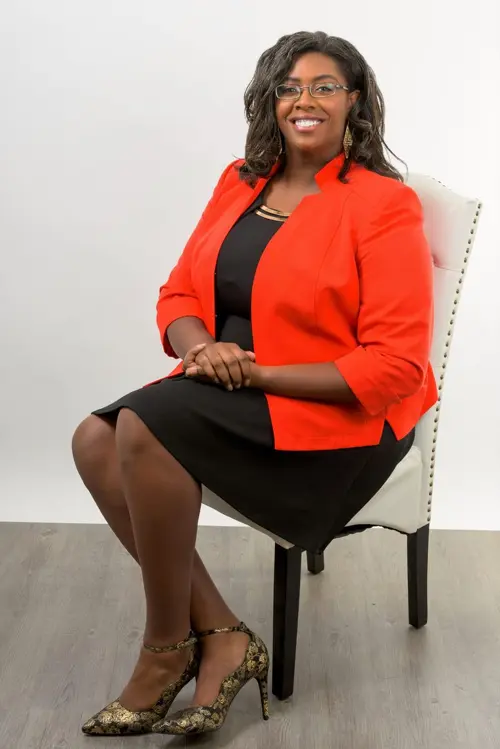 Dr. LaToya René Robertson seated in an orange blazer